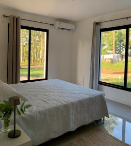 马尔多纳多CASA moderna en la floresta a 5 minutos de Punta Ballena的一间卧室设有一张床和两个大窗户