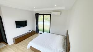 泰孟Spacious Private Villa Modern Style near beach的一间卧室配有一张床,墙上配有电视