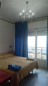 诺利B&B Solana的一间卧室配有一张带蓝色窗帘和吊灯的床。