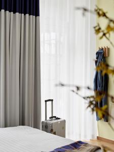 哥本哈根BRIK Apartment Hotel的一只手提箱,坐在床边,有窗