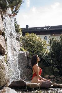 拜尔斯布龙Wellness & Genuss Resort - Engel Obertal的坐在瀑布前的女人