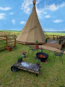ThirklebyBurtree Country House and Retreats Tipi的帐篷配有桌椅和烧烤架
