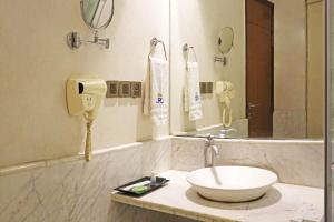 新德里Airport Hotel Claytone的一间带水槽和镜子的浴室以及一部电话