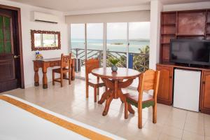 圣安德烈斯加勒比海太阳鲜花酒店 的客厅配有桌椅和电视。