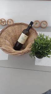 毕达哥利翁Alkisti's seaside apartments的植物旁的篮子里的一瓶葡萄酒