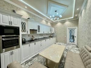 撒马尔罕Samarkand luxury apartament #8的厨房配有白色橱柜和桌子