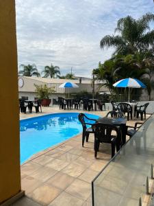 阿帕雷西达Hotel Vila dos Pescadores的一个带桌椅和遮阳伞的游泳池