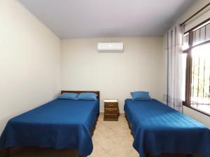 图纳里镇Casa de huespedes con piscina privada的配有两张床铺的蓝色床单和窗户