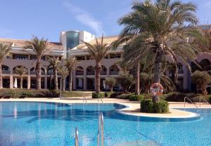 阿尔梅利马阿尔高尔夫球马尔魅力马尔酒店的一座楼前棕榈树游泳池