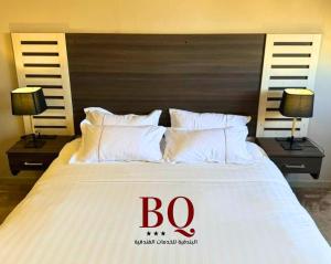 布赖代البندقية للخدمات الفندقية BQ HOTEL SUITES的一张带白色枕头的大床,上面有标志