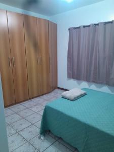 弗洛里亚诺波利斯Casa Trindade UFSC的一间卧室配有一张绿色的床和木制橱柜。