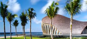 努沙杜瓦The Apurva Kempinski Bali的一座棕榈树环绕的建筑,位于大海前