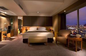 大连大连凯宾斯基饭店的一间卧室配有一张床、一张书桌和一个窗户。