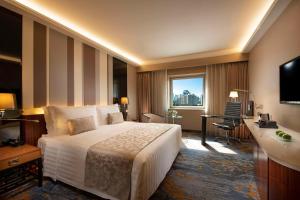 北京北京燕莎中心凯宾斯基饭店的酒店客房设有一张大床和一张书桌。