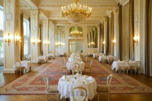 波尔托罗波尔托罗凯宾斯基宫酒店的一间配备有白色桌椅和吊灯的餐厅