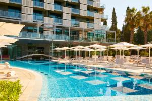 波尔托罗波尔托罗凯宾斯基宫酒店的酒店游泳池设有椅子和遮阳伞