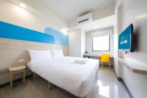 马尼拉Hop Inn Hotel North EDSA Quezon City的卧室配有一张白色大床和一张黄色椅子