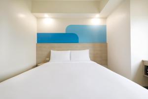 马尼拉Hop Inn Hotel North EDSA Quezon City的卧室配有白色的床和蓝色绘画
