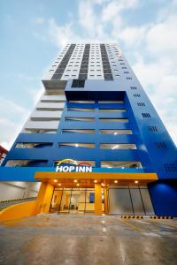 马尼拉Hop Inn Hotel North EDSA Quezon City的一座大型蓝色建筑,上面有跳跃旅馆标志
