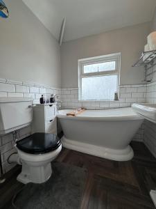 伯明翰Tayy’s Inn的带浴缸、卫生间和窗户的浴室