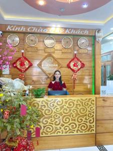 潘郎Kim Hoàn Hotel Phan Rang的墙上挂钟的柜台后面的女人