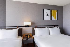 嘉义市voco Chiayi, an IHG Hotel的配有白色枕头的酒店客房内的两张床