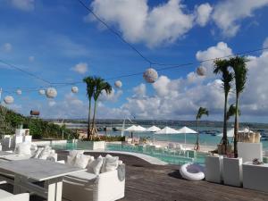 金巴兰Pronoia Beach Resort的一个带游泳池和棕榈树海滩的度假胜地