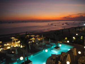 金巴兰Pronoia Beach Resort的享有海滩的夜间美景,设有游泳池