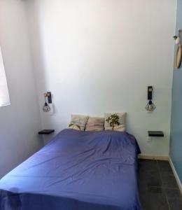 勒迪亚芒Tropi Kay' Location - Bungalow avec jacuzzi的卧室配有蓝色的床,位于白色的墙壁上