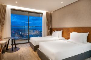 绥和市Apec Mandala Sun-Condotel Phu Yen的酒店客房设有两张床、一张桌子和一个窗户。