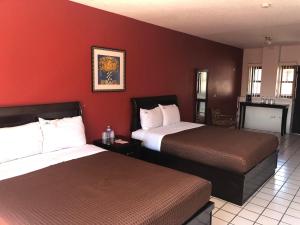恩塞纳达港HOTEL BUGAMBILIAS的红色墙壁的酒店客房内的两张床