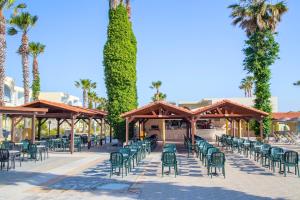 马斯蒂查里Eurovillage Achilleas Hotel的一个带绿色椅子和树木及棕榈树的庭院