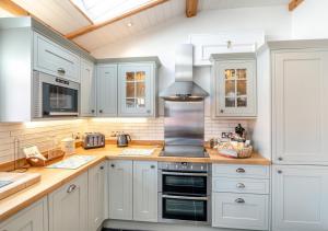 雷文斯卡2 Browcote Cottage的厨房配有白色橱柜和炉灶烤箱。