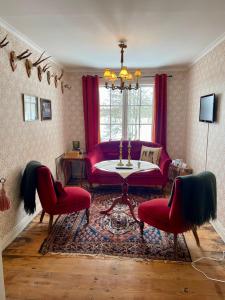 Moholm莫尔勒斯庄园酒店的客厅配有红色的沙发和两把椅子