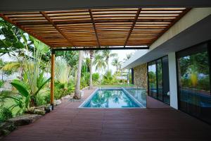 富国Kiwuki Beachfront Villa的一座带木甲板的别墅内的游泳池