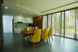富国Kiwuki Beachfront Villa的一间带木桌和黄色椅子的用餐室