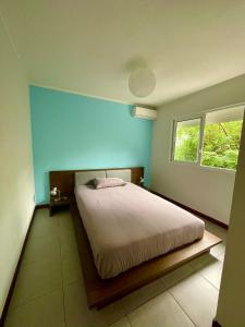 努美阿chez Gérald的一间卧室配有一张蓝色墙壁的床