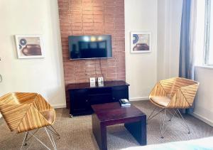 约翰内斯堡Mapungubwe Apartments的客厅配有两把椅子和墙上的电视