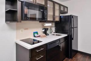 博蒙特博蒙特烛木套房酒店的厨房配有水槽和黑冰箱。