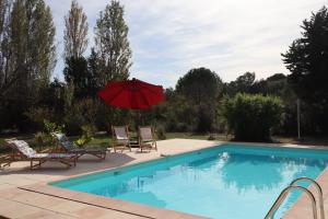 洛尔格La Maison de Blu的一个带红色遮阳伞和两把椅子的游泳池