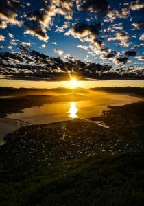 特罗姆瑟Tromsø的日落在水体上,太阳在天空中