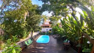弗洛里亚诺波利斯Hotel Natur Campeche的一个带椅子的木制甲板上的游泳池以及一座房子