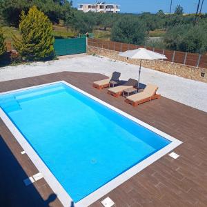 克拉法吉亚Drosoula Villa 3bdr private swimming pool的蓝色游泳池设有两把椅子和一把遮阳伞