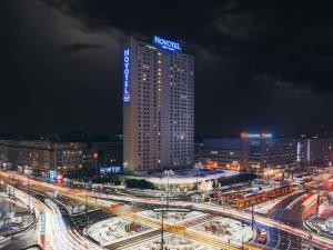 华沙华沙中心诺富特酒店的一座高大的建筑,上面有夜间标志