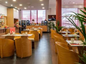 马拉加宜必思马拉加中心酒店的餐厅设有木桌和黄色椅子