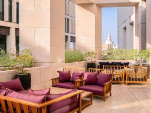 多哈Alwadi Hotel Doha - MGallery的一座带紫色软垫椅子的庭院