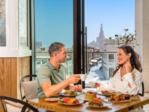 多哈Alwadi Hotel Doha - MGallery的坐在餐桌旁吃食物的男人和女人