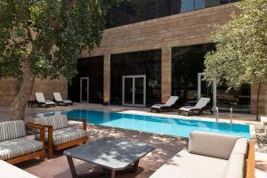埃尔比勒Bristoria Hotel Erbil的一座带躺椅和桌子的游泳池位于大楼旁