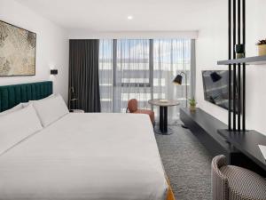 堪培拉The Sebel Canberra Campbell的酒店客房设有一张白色大床和一张桌子。