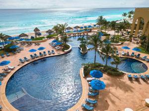 坎昆Kempinski Hotel Cancun的享有带椅子和遮阳伞的度假村游泳池的空中景致